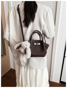 Detail of dark brown lychee leather bucket bag featuring a cute grey bunny plush charm