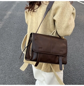 Close-up of vintage dark brown tote bag texture and wide strap on beige coat