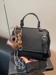 Chic black litchi pattern leather trapezoid handbag with a brown heart charm