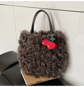Detail of plush faux fur tote bag with leather handles and cherry bag charm