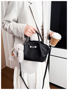 Close-up of black lychee leather bucket bag with silver lock and plush rabbit charm