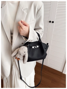 Close-up of black lychee grain leather bucket bag with silver buckle and rabbit charm