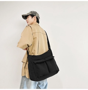 Detail of black nylon messenger bag with large front pockets and wide shoulder strap