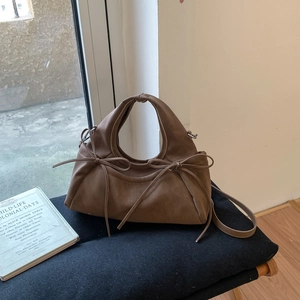 Détail macro du sac en cuir mat marron vintage avec nœud à cordon et fine bandoulière
