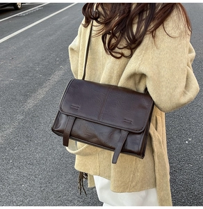 Macro detail of a dark brown vintage messenger bag with leather texture and strap accents