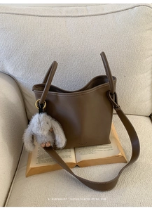 Detail of vintage bucket bag in brown lychee leather with a cute plush bunny charm