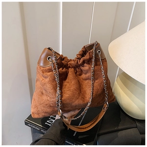 Detail of caramel suede hobo bag with quilted diamond pattern and chain strap
