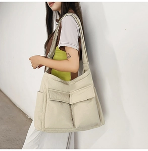 Detail of large beige canvas tote bag with front flap pockets and wide shoulder strap