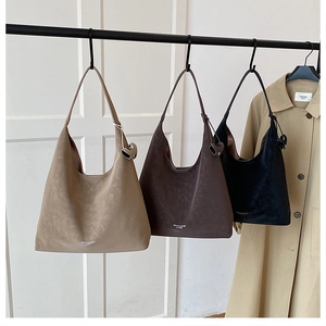 Minimalist hobo shoulder bags in beige, brown, and black displayed on a rack
