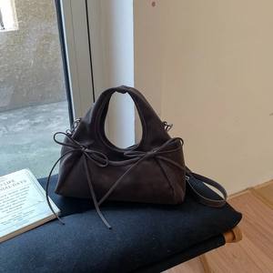 Détail du sac à main en daim marron foncé avec nœuds latéraux et bandoulière