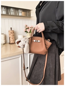Close-up of brown pebbled leather bucket bag with silver hardware and plush bunny charm