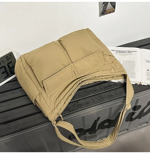 Quilted khaki nylon tote bag featuring dual front pockets on a modern striped bench
