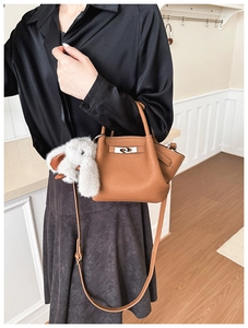 Detail of caramel leather bucket bag with silver lock and plush bunny charm