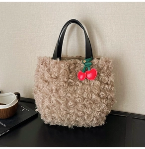 Detail of plush apricot teddy faux fur handbag with black PU leather handle and cherry charm