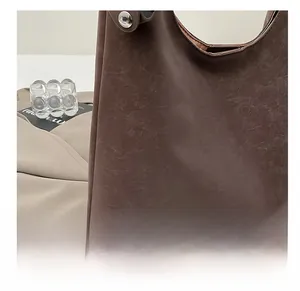 Detail of dark brown leather tote bag with silver buckle and embossed brand lettering