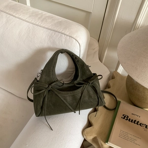 Détail du sac à main vert olive en daim avec nœuds décoratifs et bandoulière