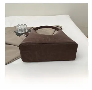 Detailed view of the wide flat base of a dark brown matte leather tote bag