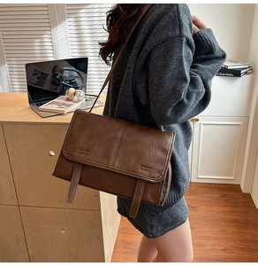 Close-up of a vintage brown leather tote bag featuring a flap lid and decorative straps