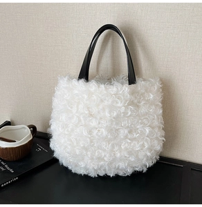 Detail of white faux fur bucket bag with black leather handle on a textured background