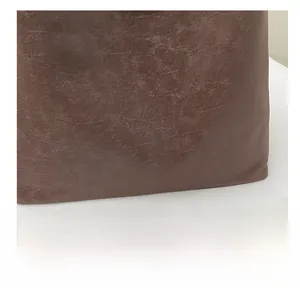 Macro detail of dark brown retro leather texture and brand lettering on the tote bag