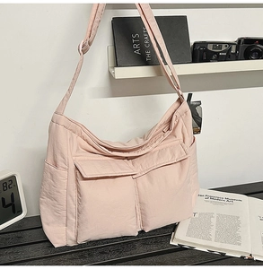 Detailed close-up of light pink nylon tote bag showing front flap pockets and texture