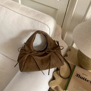 Vue détaillée du sac à main en cuir marron avec nœuds sur support en bois