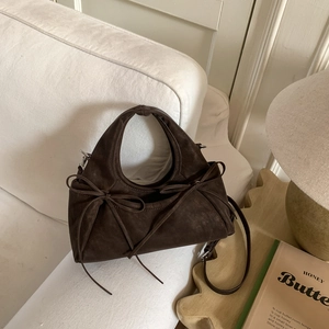 Détail du sac à main marron foncé en daim avec nœuds décoratifs et texture douce