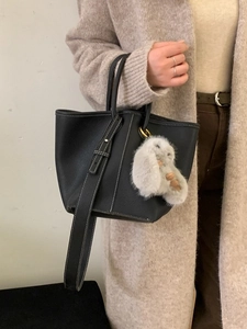 Women's black pebbled leather bucket bag with contrast stitching and a cute bunny pendant