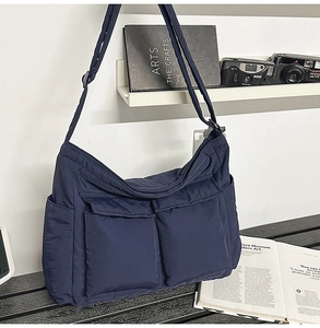 Detail of blue quilted messenger bag with large cargo pockets and adjustable strap