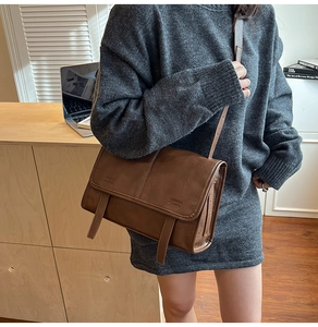 Brown vintage leather tote bag styled on model with grey sweater in office setting