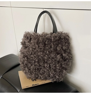 Detailed close-up of dark grey curly faux fur tote bag with black minimalist handles