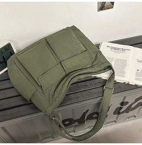 Detail of army green quilted tote bag with two large front pockets on a bench