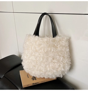 Detail of white faux shearling tote bag featuring contrast black leather handles