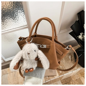 Detailed shot of brown pebble leather handbag with silver hardware and plush bunny charm