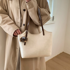Bolso tote crema grande con correa marrón oscuro y colgante de monstruo de peluche