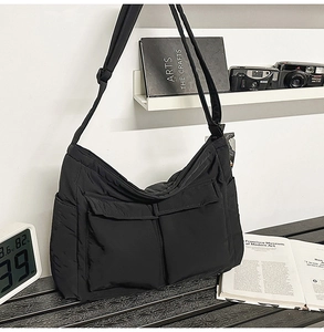 Detail of a black multi-pocket nylon tote bag styled with a camera and books