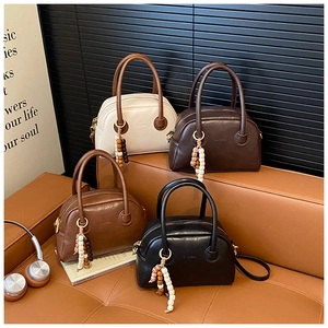 Close-up of four retro bowling bags in leather with wooden bead charms and zip detail
