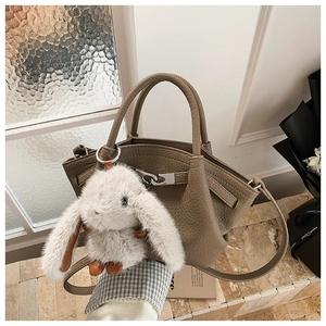 Detail of tan pebble leather bucket bag featuring silver lock and plush bunny charm