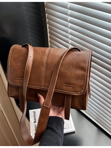 Vintage brown leather tote bag with flap design and adjustable strap in lifestyle setting