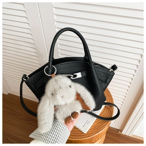 Detail of black pebbled leather bucket bag with silver hardware and grey rabbit plush charm