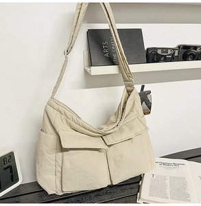 Close-up of beige canvas messenger bag with double front utility pockets and wide strap