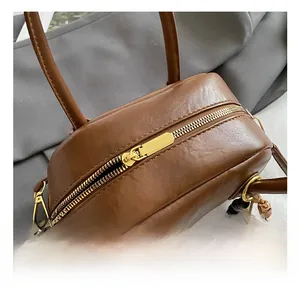 Close-up of golden zipper and brown leather handle with wooden bead decorative chain