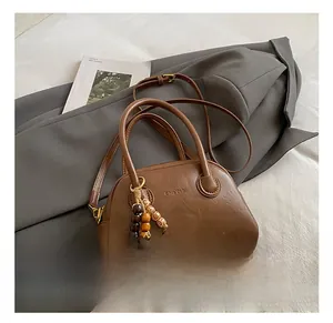 Detail of a brown retro bowling bag with textured leather and a beaded charm on a blazer