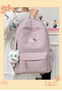 Detail eines rosa gesteppten Rucksacks mit Rautenmuster und süßem Katzen-Plüschanhänger