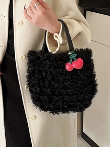 Chic black faux fur bucket bag with a pink cherry pendant and leather handle