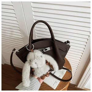 Detail of dark brown leather bucket bag with silver lock and plush bunny charm