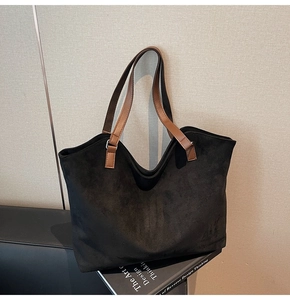Détail du grand sac cabas noir mat avec anses en cuir marron et boucles métalliques