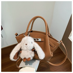 Detailed view of brown lychee grain leather bucket bag with plush bunny charm