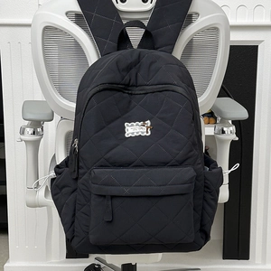 Detailansicht des schwarzen Stepprucksacks mit Rautensteppung und vorderer Reißverschlusstasche
