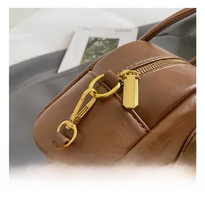 Detail view of premium brown leather texture with high-quality gold metal hook and zipper